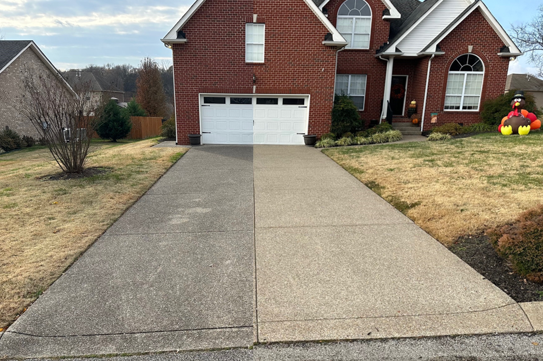 Freshly pressure washed concrete driveway in front of a brick home
